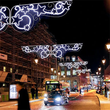 Decorative pole decorations displayed above city street.