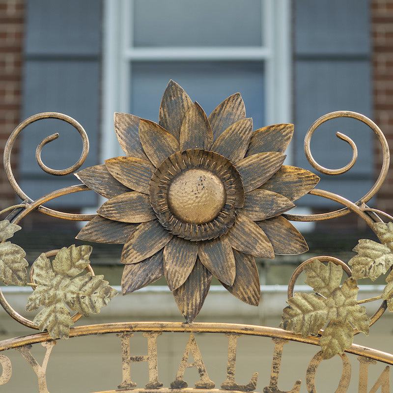 Closeup of painted iron flower at the top of the archway.