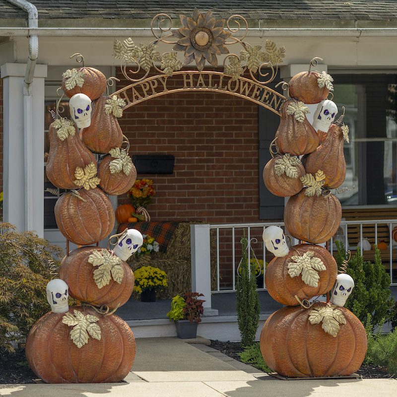 Iron archway for Halloween. Two stacks of pumpkin and skulls on either side of the words "Happy Halloween" arching across the top.