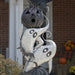 White ghosts on cemetery archway for Halloween. Black pumpkin on top of ghosts with cut out eyes and mouth for LED lights to show.