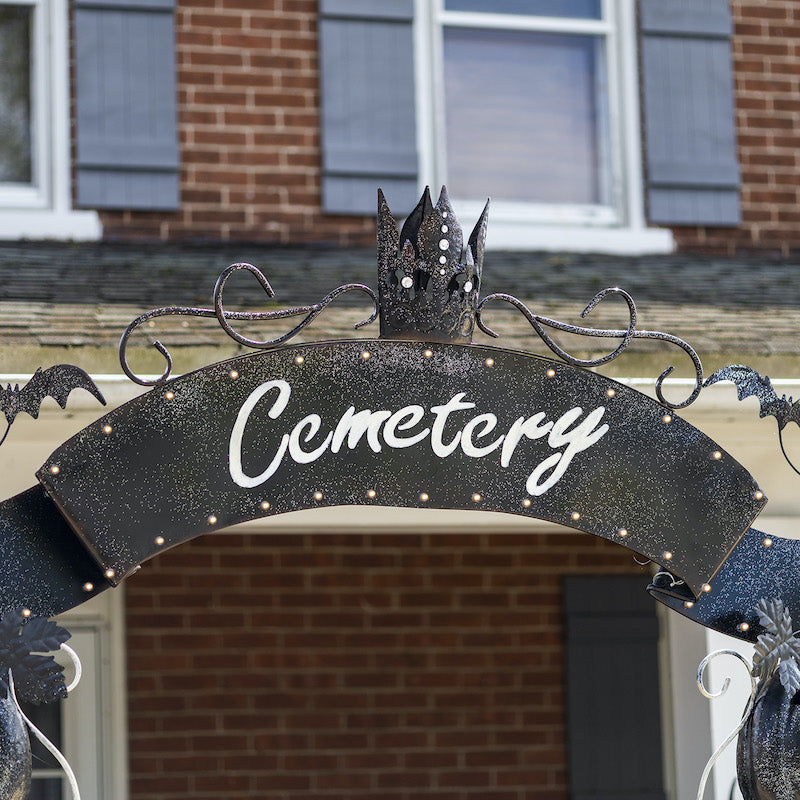 Black glittery banner with marquee lights across the top of the arch with white letters that reads, "cemetery".