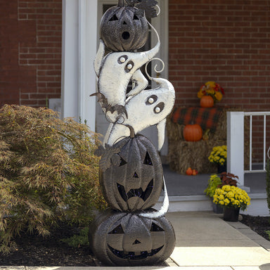 One side of archway with dark gray pumpkins and white ghosts stacked on top of each other to form side of arch.