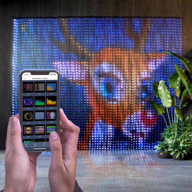 LED light curtain with Rudolph the Red-Nosed Reindeer Christmas display and person's hands holding phone with app control. 