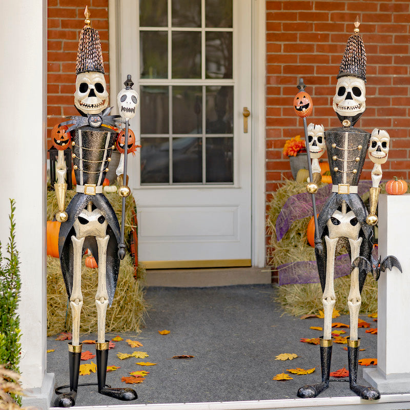 Skeleton soldier Halloween decorations shown looking similar to holiday nutcrackers. Skeleton body, black soldier suit and hat.