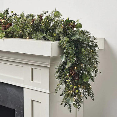 Garland made of deep green colors and textures of spruce, eucalyptus, juniper, green berries, and realistic brown pine cones.