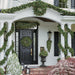 Beautiful green garland with lights and pinecones decorating outdoor area.