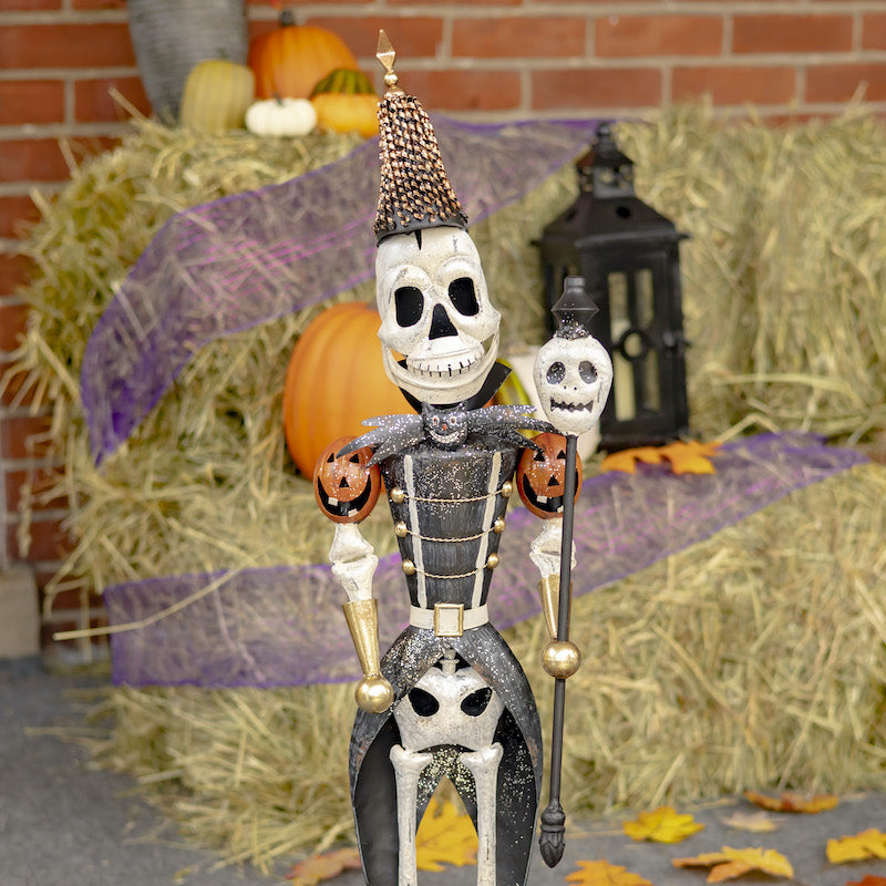 Front view of skeleton soldier with skeleton staff in hand. pumpkin shoulders and boney body with black soldier coat.