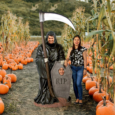 Grim Reaper Photo Op Statue - Large with people posing in a pumpkin patch